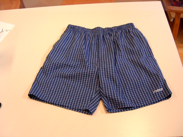 Badehose, sog. Badeshort
- von der Taille bis zum halben Oberschenkel reichend,
- aus 65 % Polyester und 35 % Baumwolle gewebt,
- mit einem gewirkten Innenslip aus 100 % Polyester,
- in der Taille einen elastischen Bund und eine Zugkordel aufweisend,
- seitlich je eine Einschubtasche mit einem vollständig durchgehenden Klettverschluß.