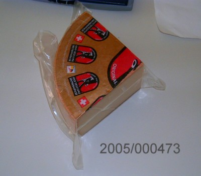 Runder, schnittfester Käselaib mit Rinde/Schmiere, vereinzelt kleine Rundlochungen aufweisend, Käse aus Kuhmilch mit bergkäseartigem Geschmack.