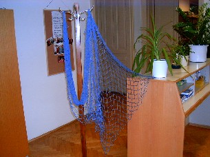 Geknüpftes Netz aus Bindfäden
- aus gefärbter Baumwolle
- mit offenen, abgeknoteten Zellen
- konfektioniert (abgepasst hergestellt)

Die Ware dient zu Dekorationszwecken eines Schaufensters.