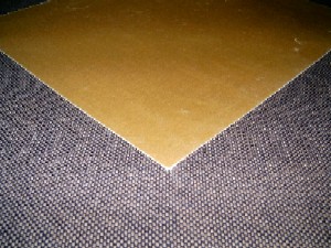 Gewebe aus Glasseidensträngen (Rovings), 
- 0,1 mm dicke, gelbe, glatte, biegsame Bögen eines Glasfasergewebes (1 lagig) das mit Epoxydharz getränkt ist, 
- aus Glasseidensträngen in dem zusammengefasste Glasfäden annähernd parallel liegen (Rovings), 
- zur besseren Stabilität mit einem Bindemittel (Epoxydharz) verfestigt,