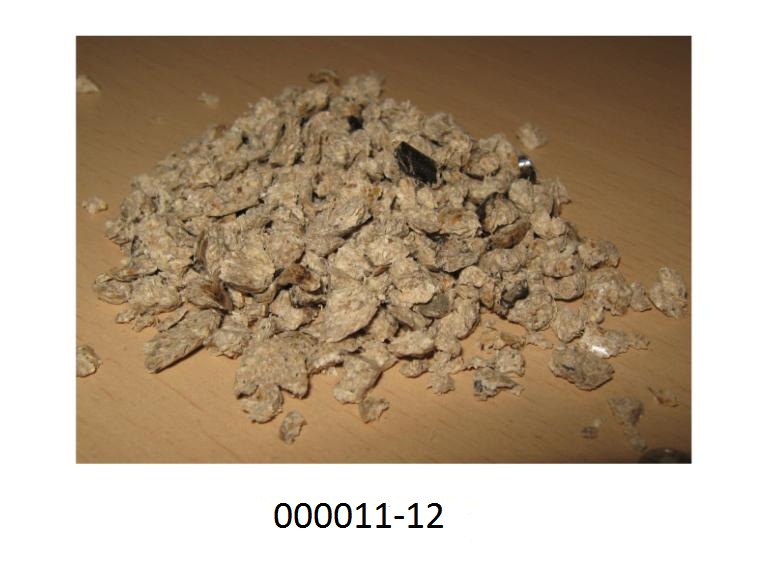 Hellbraune, sowie zum Teil dunkelbraune, aus Sägespänen bestehende Bruchstücke von Pellets, vermischt mit einem hellbraunen Pulver.