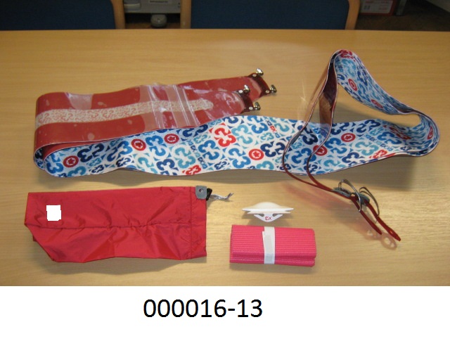 Ausrüstungsgegenstand für die körperliche Ertüchtigung (Zubehör), in Form von Skifellen, vorliegend in einer Warenzusammenstellung, bestehend aus
- einem Skifell
-- ca. 170 cm lang und 14 cm breit,
-- an den beiden Enden mit einer Fixiereinrichtung aus unedlem Metall und an der der Skispitze zugewandten Seite mit einer Kunststoffschlaufe ausgestattet,
-- bestehend aus einem mehrlagigen Erzeugnis : einer dem Boden zugewandten, buntbedruckten Wirkware aus synthetischen Spinnstoffen auf Polyamidbasis mit eingearbeiteten Polfäden, welche auf eine Höhe von ca. 1mm geschnitten sind, und deren Lage der eines natürlichen Felles ähnelt; einem aufkaschierten, rot gefärbten Gewebe aus synthetischen Spinnstoffen auf Polyacrylnitrilbasis; und einer gelartigen, farblosen Klebstoffschicht auf der Rückseite, welche mit einer Kunststofffolie abgedeckt ist. Nach Abzug der Folie wird das „Steigfell“ auf die Lauffläche des Skis geklebt und mit den Fixiereinrichtungen am Ski fixiert.
- einem pinkfarbenen Flächenerzeugnis
-- gitterartig gearbeitet, ca. 200 x 15 cm groß,
-- bestehend aus einem Gewirke aus synthetischen Filamentgarnen auf Polyesterbasis, welche vollständig mit einer geschäumten Kunststoffmasse aus weichgemachtem PVC ummantelt ist (rutschfeste Unterlage zur Abdeckung der Klebeschicht der Skifelle)
- einer geformten Schneidevorrichtung
-- aus Kunststoff, mit zwei schräggestellten Klingen
-- dazu bestimmt, überstehende „Fellteile“ abzuschneiden, um an die Form des jeweiligen Skis angepasst zu werden
- einem bedruckten, sackähnlichen Behältnis
-- bestehend aus einem dichten Gewebe auf Polyfamidbasis, rückseitig mit einem sehr dünnen Kunststofffilm überzogen (mit freiem Auge nicht erkennbar),
-- dient der Aufbewahrung.