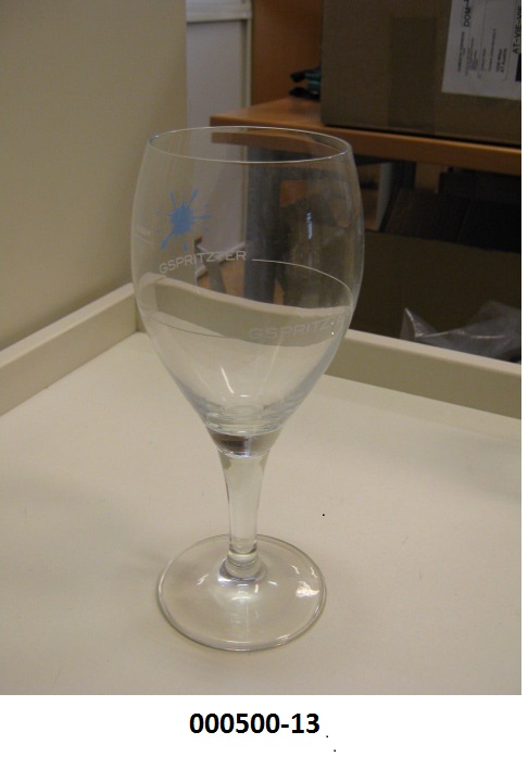 Glasware in Form eines Weinkelches
- ca. 19 cm hoch und mit einem Durchmesser von ca. 6,2 cm, mit Stiel,
- mechanisch gefertigt aus Soda-Kalkglas,
- mehrfärbig bedruckt mit einem „Farbklecks“ und 2 Füllmarken,
- zur Verwendung bei Tisch/in der Küche vorgesehen.
(Abbildung siehe Anlage)