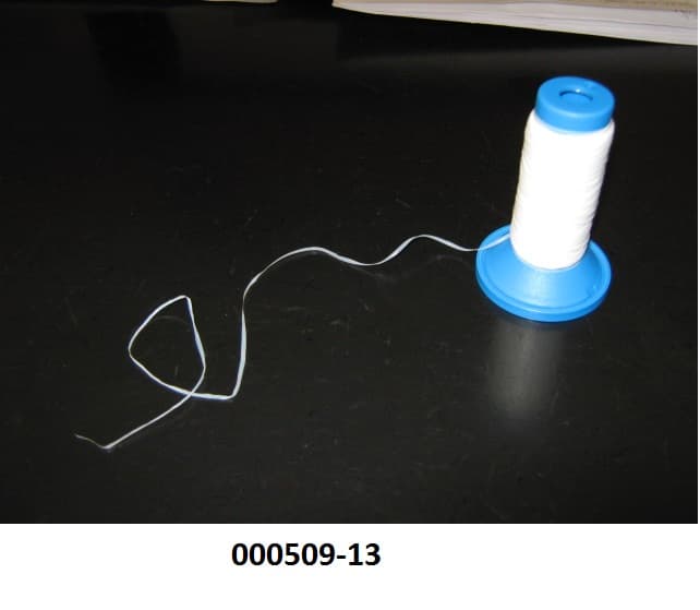 Streifen 
- bestehend aus einer synthetischen Spinnmasse aus Polytetrafluorethylen (103,27 tex), 
- ca. 1,44 mm breit und ca. 0,04 mm dick,
- aufgewickelt auf einem Originalkops.
(Abbildung siehe Anlage)