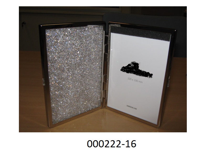 Ware aus unedlen Metallen, in Form eines Bilder-/Fotorahmens,
- mit den Abmessungen von ca. 15,7 x 10,9 x 1,9 cm,
- zweiflügelig, über Scharnieren aufklappbar,
- bestehend aus verzinktem Messing, mit Glasscheibeneinlage,
- ein Flügel ist mit Strasssteinen mit geschliffenen Kanten gefüllt, in den anderen Flügel können zwei Fotos mit einer maximalen Größe von 15 x 10 cm eingesetzt werden.
Als wesensbestimmend dieser Warenzusammensetzung wird der Metallrahmen angesehen.
