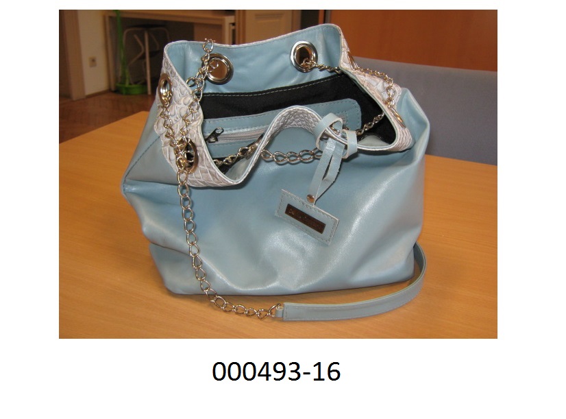 Behältnis in Form einer Handtasche
- in der Form eines Seesackes verarbeitet,
- mit einer Außenseite aus einem einfärbigen Leder und Innenfutter ausgestattet,
- mit einer mit Zippverschluss verschließbaren Innen- und Außentasche versehen,
- am oberen Taschenrand mit einem ca. 5cm breiten Streifen in Reptilienlederoptik verarbeitet, welcher Metallösen aufweist durch welche eine Kette aus unedlem Metall geführt ist um die Tasche zu verengen,
- mit vier im Taschenboden eingearbeiteten Metallknöpfen zum Abstellen,
- mit einem Schulterriemen bzw. Handgriff ausgestattet.