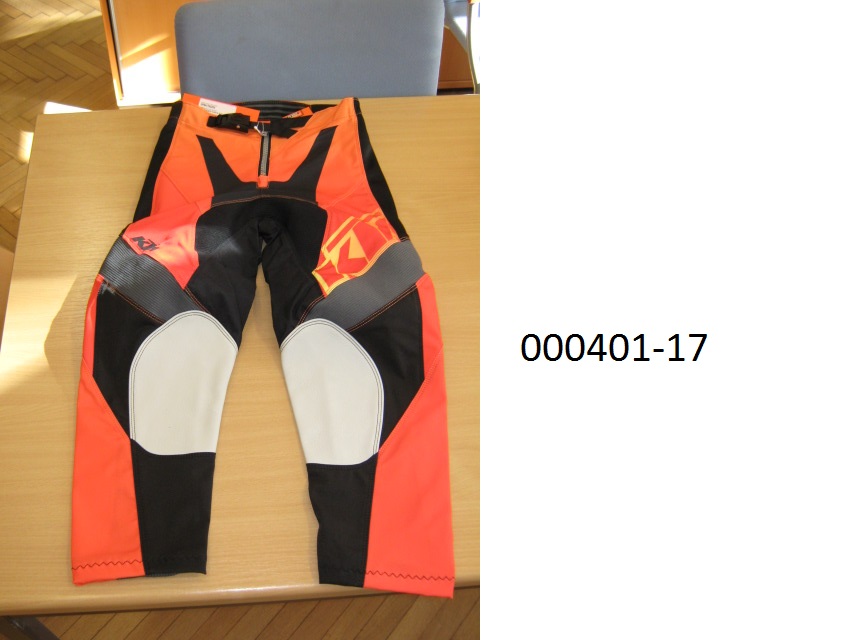 lange Hose (Motorradhose)
- beide Beine einzeln umschließend und bis zu den Knöcheln reichend,
- mittels Zippverschluss vorne verschließbar,
- verarbeitet mit einer im Bund integrierten Gürtelschnalle, links über rechts verschließbar (für Männer oder Knaben), 
- bestehend aus patchworkartig zusammengenähten, bedruckten Gewirken und Geweben aus synthetischen Spinnstoffen auf Polyesterbasis, das Gewebe überwiegt, 
- im Gesäßbereich rückseitig mit einer dünnen Schicht auf PUR-Basis (mit freiem Auge sichtbar) überzogen,
- im Kniebereich mit eingenähten Lederteilen ausgestattet,
- aufgrund der Verarbeitung als Motorradhose für Knaben erkennbar, keine Arbeits- oder Berufsbekleidung.
(Abbildung siehe Anlage)