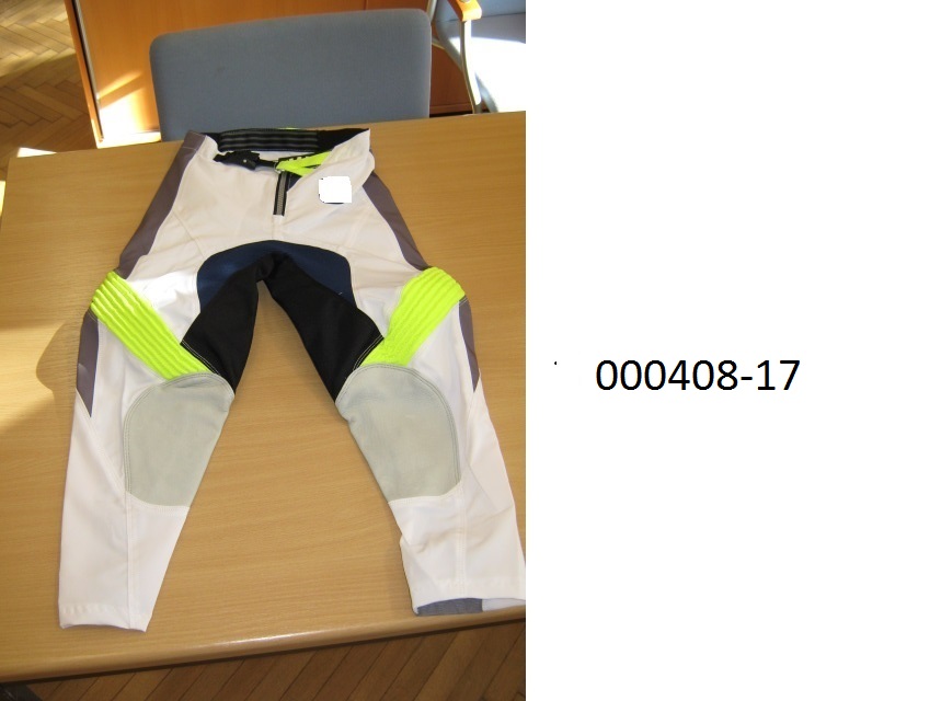 lange Hose (Motorradhose)
- beide Beine einzeln umschließend und bis zu den Knöcheln reichend,
- mittels Zippverschluss vorne verschließbar,
- verarbeitet mit einer im Bund integrierten Gürtelschnalle, links über rechts verschließbar (für Männer oder Knaben), 
- gefüttert mit einer netzartigen Wirkware,
- bestehend aus patchworkartig zusammengenähten Gewirken und Geweben aus synthetischen Spinnstoffen auf Polyesterbasis, welche auf der Rückseite teilweise mit einer Folie auf PUR-Basis beschichtet sind (mit freiem Auge erkennbar), die nicht beschichteten Flächenerzeugnisse aus Gewebe überwiegen,
- im Innenseitenbereich der Unterschenkel mit eingenähten Lederteilen ausgestattet,
- im linken Unterschenkel mit einem Prallschutz in Form von zwei geschäumten, mit Spinnstoff überzogenen Kunststoffplatten verarbeitet,
- aufgrund der Verarbeitung als Motorradhose für Knaben erkennbar, keine Arbeits- oder Berufsbekleidung.
(Abbildung siehe Anlage)
