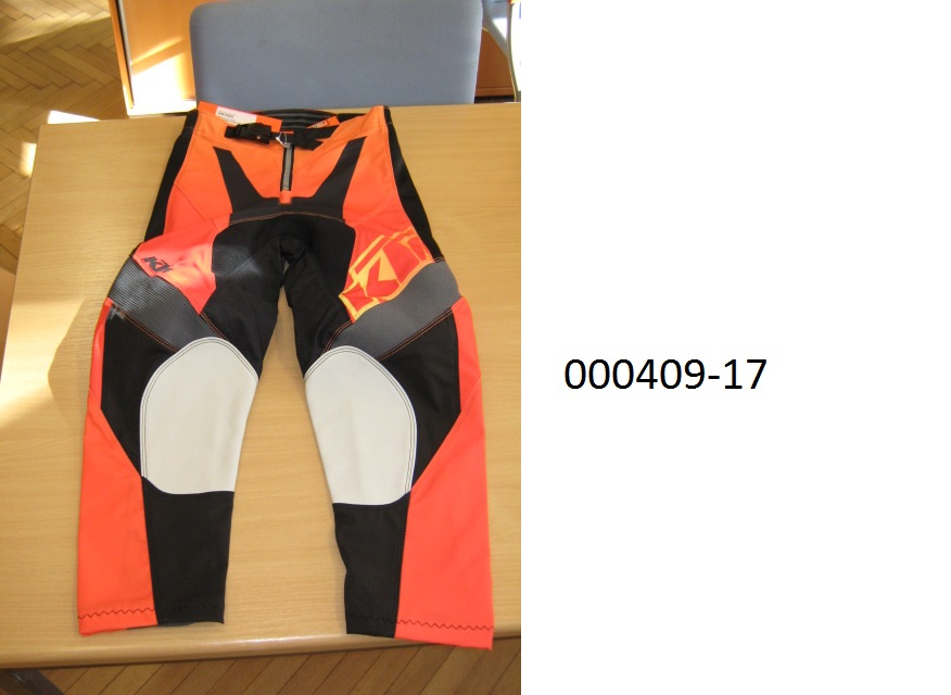 lange Hose (Motorradhose)
- beide Beine einzeln umschließend und bis zu den Knöcheln reichend,
- mittels Zippverschluss vorne verschließbar,
- verarbeitet mit einer im Bund integrierten Gürtelschnalle, links über rechts verschließbar (für Männer oder Knaben), 
- bestehend aus patchworkartig zusammengenähten, bedruckten Gewirken und Geweben aus synthetischen Spinnstoffen auf Polyesterbasis, das Gewebe überwiegt, 
- im Gesäßbereich rückseitig mit einer dünnen Schicht auf PUR-Basis (mit freiem Auge sichtbar) überzogen,
- im Kniebereich mit eingenähten Lederteilen ausgestattet,
- aufgrund der Verarbeitung als Motorradhose für Knaben erkennbar, keine Arbeits- oder Berufsbekleidung.
(Abbildung siehe Anlage)