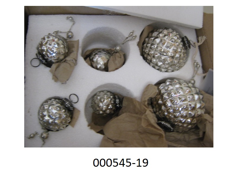 Weihnachtsartikel, in Form eines Sets Zieranhänger, 
- bestehend aus 6 Stück Kugeln in 3 Größen (Höhe 11, 9, 7cm; Durchmesser 10, 9, 5cm)
- gearbeitet aus einem Hohlkörper aus Glas (Antiksilber-Optik), mit einer noppenartigen Struktur verarbeitet,
- mit einer Aufhängevorrichtung aus unedlen Metallen mit Öse ausgestattet.
Aufgrund der Kombination von schimmernder Oberfläche, Form und der Aufhängevorrichtung handelt es sich bei dem Set dem Gesamteindruck nach um Dekorationsartikel für Weihnachtsbäume (Christbaumschmuck), die nach herkömmlichem Brauch zur traditionellen Ausgestaltung der Advents- und Weihnachtszeit verwendet werden.
Der Glasanteil überwiegt gegenüber dem unedlen Metall.
(Abbildung siehe Anlage, Materialangaben laut Antragsteller)
