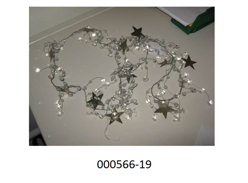 Ware aus Glaskurzwaren, in Form einer Girlande
- mit einer Länge von ca. 183cm
- gearbeitet aus einem biegsamen Draht, an welchem geschliffene Glassteine und Sterne aus einem unedlen Metall fixiert sind,
- das Glas (90%) überwiegt gegenüber dem Metall (10%) und ist daher als wesensbestimmend anzusehen.
Eine Einreihung als Weihnachtsfestartikel kommt nicht in Betracht, da die Ware neutral gestaltet ist und keinen Bezug zum Weihnachtsfest aufweist.
(Abbildung siehe Anlage, Materialangaben laut Antragsteller)