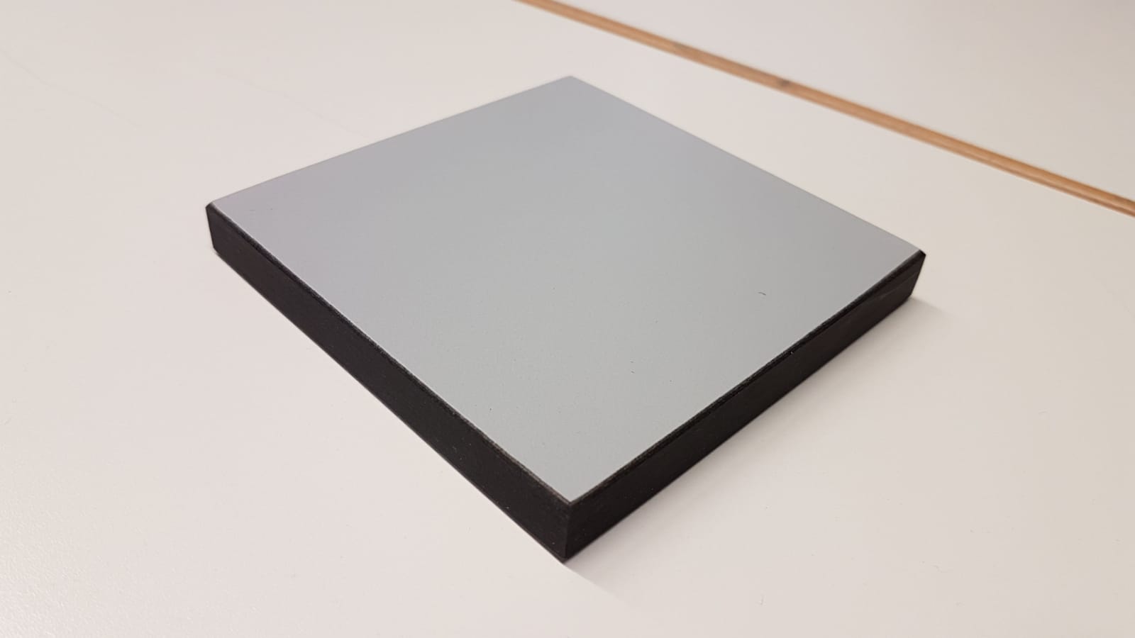 Andere Platte aus einem Kondensationspolymerisationskunststoff, nicht aus Zellkunststoff, und zwar eine rechteckige, an ihren Oberflächen glatte und schmutzigweiße, im Inneren schwarzgraue, unregelmäßig schieferähnlich geschichtete Platte, bestehend aus einzelnen, mit Phenolharz getränkten und unter hohem Druck gepressten Papierlagen; die äußeren Lagen bestehen aus gefärbtem, mit Melaminharz getränktem Papier, wobei der Phenolharzanteil überwiegt (alle Daten beruhen auf den Angaben des Antragstellers).