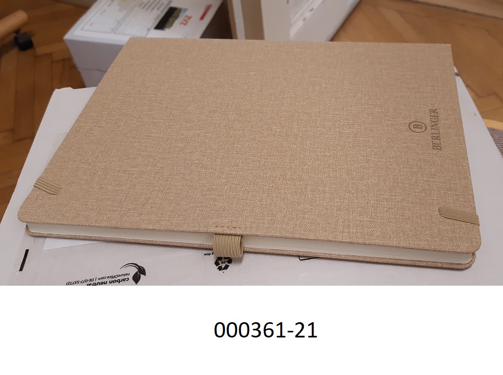 Notizbuch aus Papier
- mit den Maßen von ca. 19,2 x 26,2cm,
- gebunden, mit einem festen Einband aus mit Kunststoff in Textiloptik umhüllter Pappe (mit Ausnahme des Rückens), welcher auf den Außenseiten mit Schaumkunststoff gepolstert und mit lederartig geprägter Kunststofffolie überzogen ist,
- mit Blättern, welche auf den ersten beiden Seiten beidseitig vollständig liniert bedruckt, danach glatt ausgeführt sind,
- mit einem am Buchrücken angebrachten Band aus Spinnstoffen als Lesezeichen,
- mit einem elastischen Band zum Verschließen des Blockes und einer elastischen Schlaufe für ein Schreibgerät ausgestattet,
- ohne Kalendarium.
 (Abbildung siehe Anlage)