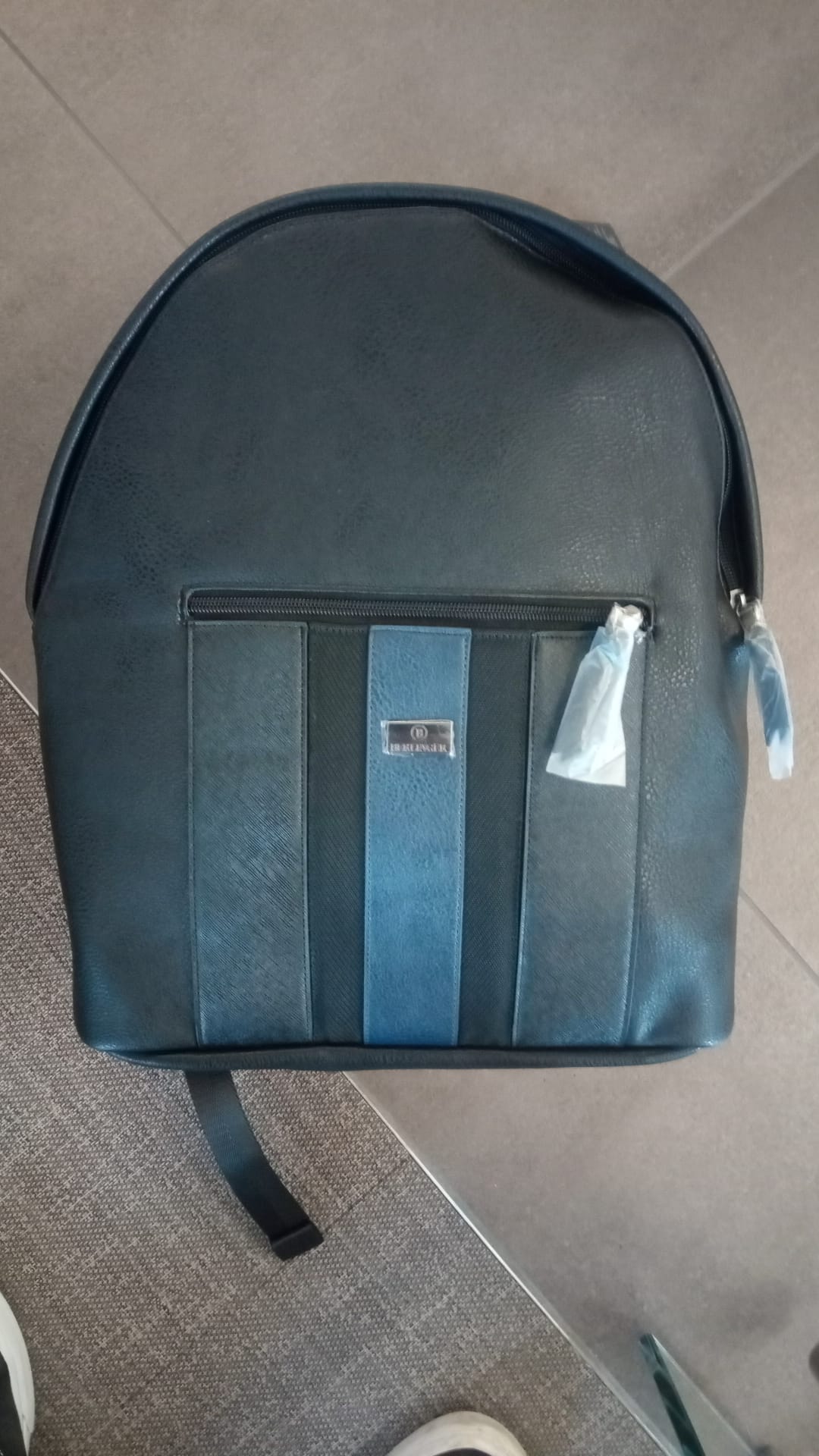 Behältnis in Form eines Rucksackes
- mit den Maßen von ca. 40 x 32 x 10cm,
- bestehend aus einer Kunststofffolie auf Polyurethanbasis, 
- an der Oberseite mit einem Tragegriff ausgestattet,
- mit 2, mittels Zippverschluss verschließbaren Fächern verarbeitet, wobei das größere Fache innen noch ein weiteres, mittels Klettverschluss verschließbares Fach aufweist,
- an der Rückseite gepolstert,
- verpackt in einem Faltkarton.
(Abbildung siehe Anlage)
