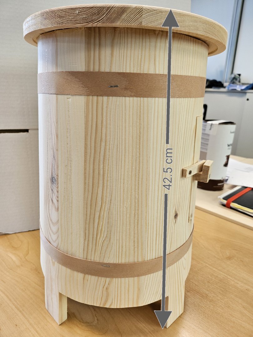 Sitzmöbel, in Form eines Hockers
- zylinderförmig gearbeitet, mit einer Höhe von ca. 42,5cm,
- komplett aus Holz bestehend (Kieferholz laut Antragsteller),
- ungepolstert, auf der Sitzfläche mit einem Aufdruck versehen,
- seitlich mit einer Öffnung versehen, um (Likör)flaschen (nicht Gegenstand dieser VZTA) im Inneren des Hockers zu verstauen,
- dazu bestimmt, auf den Boden gestellt zu werden und dient der Einrichtung von unterschiedlichen Räumen in einer Wohnung.
(Abbildung siehe Anlage)