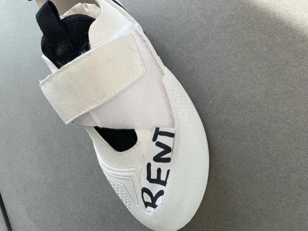 Schuh 
- den Knöchel nicht bedeckend,
- mit einem geschlossenen Blatt verarbeitet, mittels Klettverschluss verschließbar,
- mit einer leicht gebogenen Sohle aus Kautschuk, nicht profiliert,
- mit einem Obermaterial aus einem chemisch verfestigten Vlies auf Polyurethanbasis,
- Länge der Innensohle länger als 24cm,
- nicht als Damen- oder Herrenschuh erkennbar,
- in einem Sackerl aus Kunststofffolie verpackt.
Aufgrund der Form, des Schnittes und Aussehens als Kletterschuh in Kletterhallen vorgesehen, daher Einreihung als Trainingsschuh.
(Abbildung siehe Anlage)