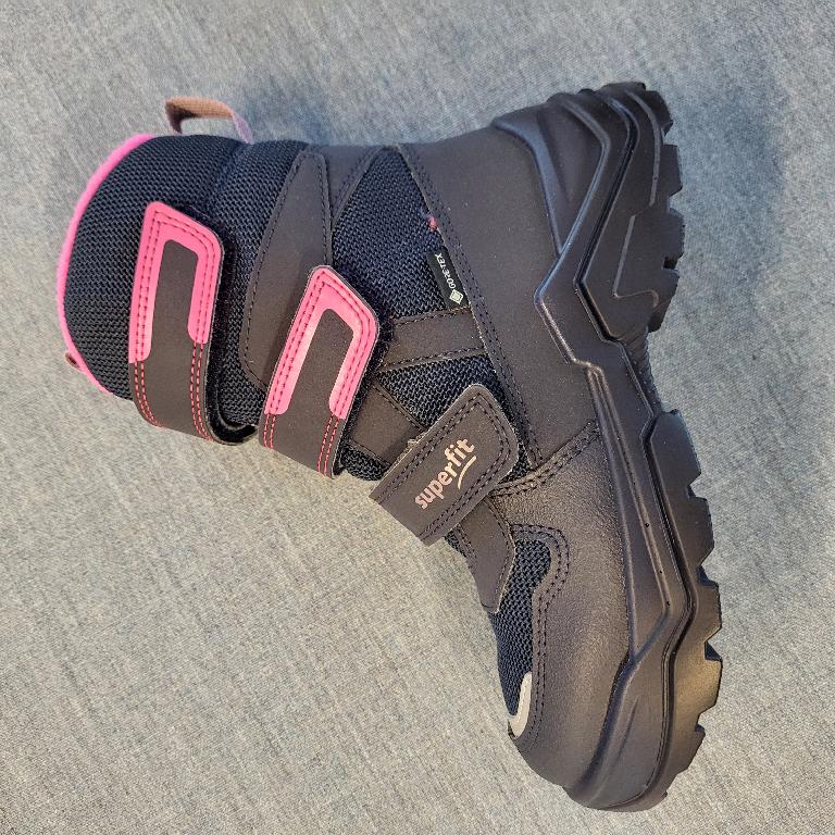 Schuh :
- den Knöchel, jedoch nicht die Wade bedeckend, 
- mit einem geschlossenen Blatt und drei Klettverschlüssen verarbeitet;
- mit einer profilierten Laufsohle aus Kunststoff versehen;
- bestehend aus einem Oberteil aus einem auf das Futter aufgebrachten Gewirke aus Polyester und Kunststoffteilen auf Polyurethanbasis bzw. aus aufgenähten Verstärkungsteilen aus Kunststoff; wenn man jene Teile, welche Verstärkungs- und Zubehörteile darstellen, außer Acht lässt, überwiegt der Spinnstoffanteil an der äußeren, sichtbaren Schicht des Obermaterials;
- nicht als Mädchen- oder Knabenschuh erkennbar;
- Länge der Innensohle weniger als 24cm;
- verpackt in einem Faltkarton.
Schuhe, welche ausschließlich oder im Wesentlichen beim Gehen getragen werden.
Gem. der Erläuterungen zur KN zu Position 6404, 3. Absatz, bilden Schuhe, welche ausschließlich oder im Wesentlichen beim Gehen, Trekking, Wandern oder Bergsteigen getragen werden, die Ausnahme zu "Schuhen für Sportzwecke".
Aufgrund der Verarbeitung, welche die Stabilität bzw. Festigkeit des Fußes im Schuh nicht gewährleistet, ist der gegenständliche Schuh nicht für Trainingszwecke (Sportzwecke) geeignet.
(Abbildung siehe Anlage)