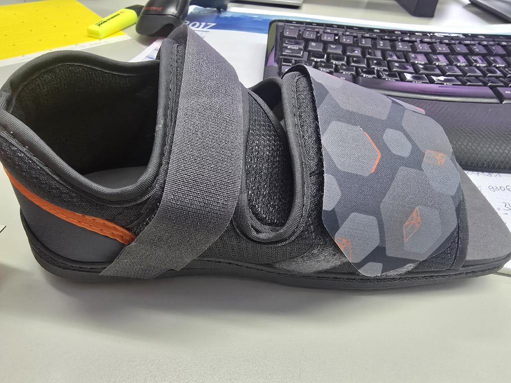Postoperativer Schuh
- mit einem Oberteil aus auf das Futter aufgenähten bzw. geklebten Gewirken aus Polyethylen, im Zehenbereich offen,
- mit zwei Klettverschlusslaschen verschließbar,
- mit einer profilierten Laufsohle aus Kunststoff und einer weichen Innensohle verarbeitet,
- ohne rechts oder links Ausrichtung,
- Länge der Innensohle mehr als 24cm,
- nicht als Damen- oder Herrenschuh erkennbar,
- verpackt in einem Karton,
- aufgrund der Verarbeitung als orthopädischer Schuh erkennbar.
(Abbildung siehe Anlage)
