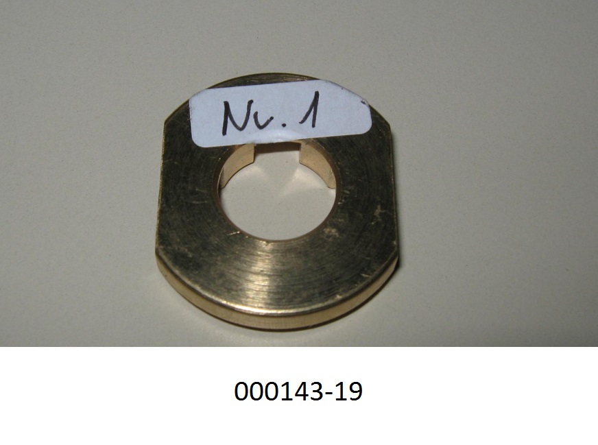 Messingfarbene Scheibe mit einer Dicke von 5,9 mm, welche auf zwei gegenüberliegenden Seiten flach ausgeführt ist. Die Scheibe hat eine mittige Bohrung von 13 mm, die auf einer Seite kreuzförmig angelegte Ausnehmungen aufweist und deren Kante auf dieser Seite rund abgeschrägt ist.
Mit einem Gehalt von mehr als 59 GHT an Kupfer (Cu), sowie Anteilen an Zink (Zn), Blei (Pb), Zinn (Sn), Eisen (Fe), Nickel (Ni) und anderen Elementen.
Die Scheibe besteht aus Messing.
(Abbildung siehe Anlage)