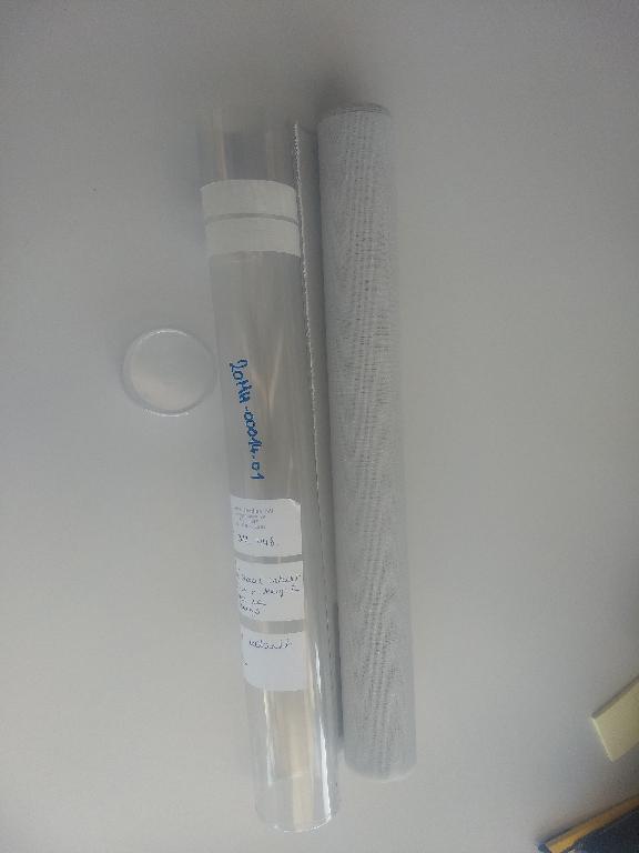 Een stuk rechthoekig versneden weefsel in platbinding, op rollen, aan één kant voorzien van een lijmlaag met zwakke lijmkracht, zonder beschermfolie. De lijmlaag is niet met het blote oog zichtbaar.
Het weefsel is samengesteld uit stapelvezels van polyester en ecru van kleur.
Het wordt gebruikt als afneembare vensterbekleding (blindering en zonnewering).
Het product wordt aangeboden op een rolletje van 45 cm breed en 150 cm lang.