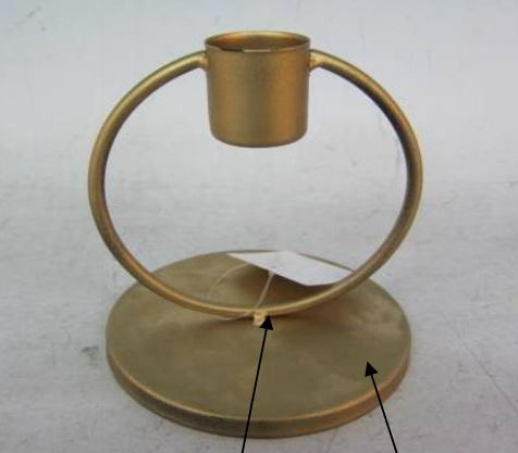 Een metalen kandelaar bestaande uit een ronde basis met daarop een rechtopstaande ring waar bovenaan een houder, waarin een smalle kaars kan worden geklemd, is bevestigd.

Volgens opgave is het geheel vervaardigd van bronskleurig geverfd onedel metaal.

Het artikel heeft een diameter van 10 cm en een hoogte van 11 cm, de eigenlijke kaarsenhouder heeft een diameter van 2,1 cm.

Er zijn geen aanduidingen dat deze kandelaar “met de hand zou zijn vervaardigd”.