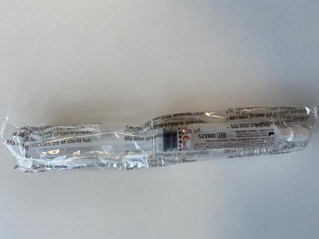 Een spuit van polypropyleen zonder naald en voor eenmalig gebruik. De spuit is gevuld met een fysiologische zoutoplossing. Deze dient voor het spoelen van vasculaire katheters.