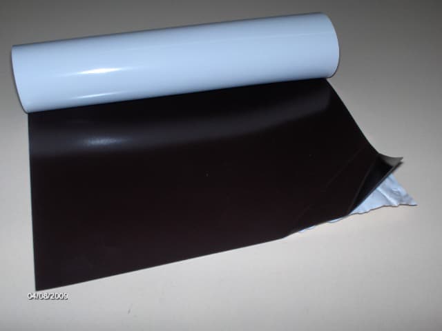 Гъвкав магнит на ролки с PVC и UV покритие. Изделието е двуслойно. Първият слой, който преобладава като дебелина и тегло е с тъмен цвят и се състои от стронциев ферит, агломериран с хлориран полиетилен.  Този слой има свойствата на постоянен магнит.   Вторият слой е бял на цвят и е прикрепен чрез залепване към първия. Състои се от поливинилхлорид с UV покритие. Изделието се използва за изработването на рекламни стикери за закрепване към метални повърхности след предварително отпечатване на рекламни изображения върху слоя от поливинилхлорид и изрязването им във форма.