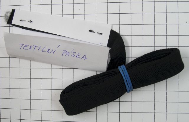 Dle údajů žadatele se jedná o textilní pásku.
Popis a složení výrobku: Předložený vzorek je černý pruh textilního materiálu o šířce 1,5 cm a délce 362 cm. Je zhotoven ze dvou druhů vláken – střižových dvojmo skaných a nekonečných, syntetických v keprové vazbě. Vlákna osnovní nitě jsou bavlněná (plochá se zákrutem S), vlákna útkové nitě jsou syntetická (PES) nekonečná kadeřavá. 
Účel použití výrobku: Jak uvádí žadatel, textilní páska se používá jako vnitřní výztuha oděvů, podšívek, povlaků, rukavic, pokrývek hlavy, pracovních oděvů, oděvních koster atd.
Balení výrobku: Dováží se v kartonech o rozměrech (51 x 51 x 23) cm, natočený v návinech po 50 nebo 100 m. Obsah kartonu je 5000 bm. Vyrábí se v šířích od 5 mm do 40 mm.
