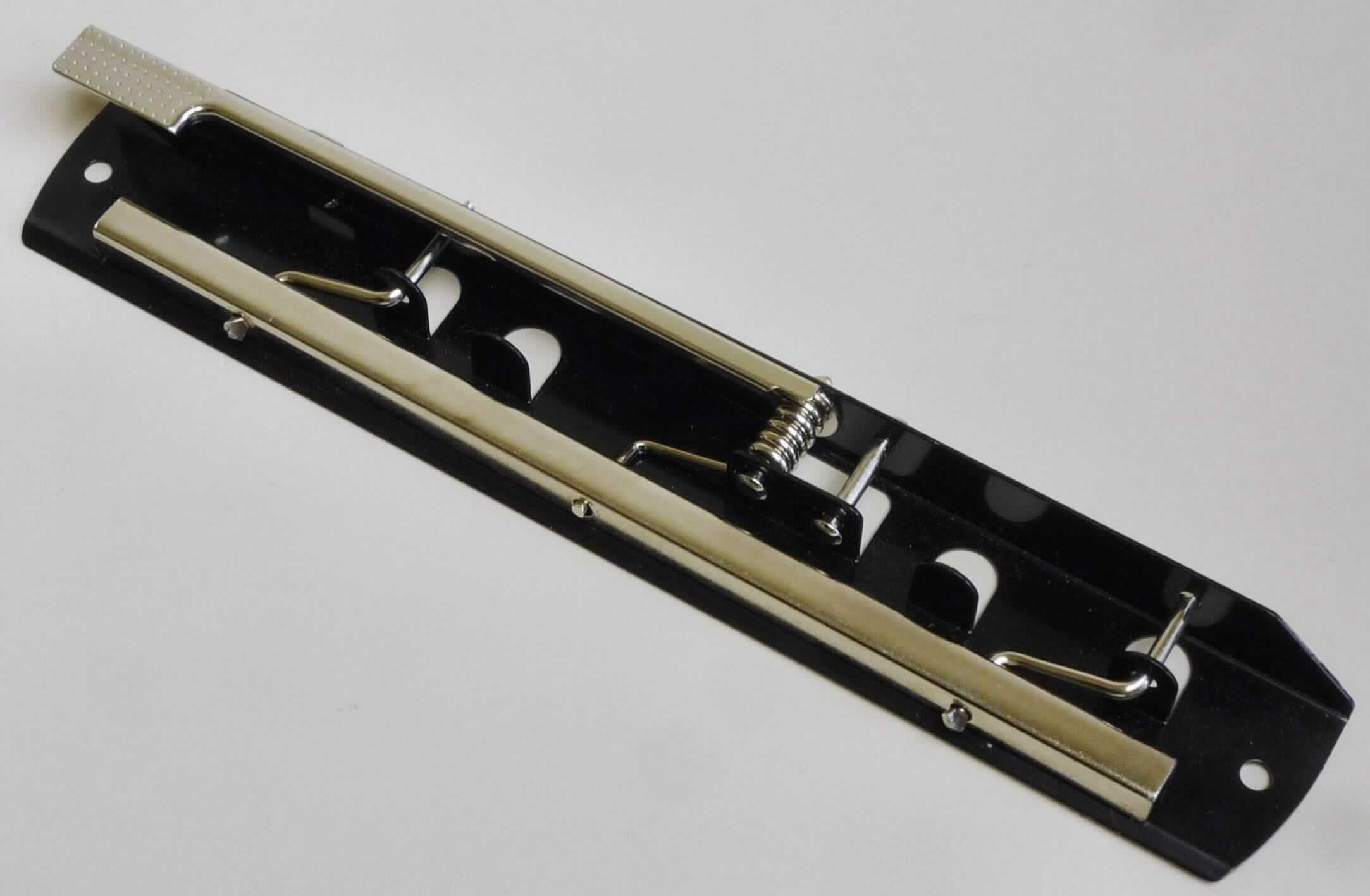 Es handelt sich um aus unedlem Metall gefertigte Klemmvorrichtungen, bestehend jeweils aus einer abgewinkelten, nahezu rechteckigen Grundplatte (ca. 203 mm x 30 mm), die mit verschiedenen Lochungen versehen ist. 
Auf der Platte ist ein Hebel mit einer Feder und einem U-förmigen Klemmprofil befestigt. Mit dem Hebel kann die Klemmmechanik geöffnet, geschlossen und fixiert werden. Zur Fixierung wird der lange Hebel im geschlossenen Zustand mittels einer angebrachten Nase an der Seitenplatte verankert. Die Ware dient der Festklemmung von ungelochtem Papier auf Klemmbrettern oder in schmalen Ordern.

Abbildung siehe Anlage. 

Derartige Erzeugnisse gehören als "den Aktenklammern ähnliches Büromaterial, aus unedlen Metallen" zum TARIC-Code 8305 9000 00.
