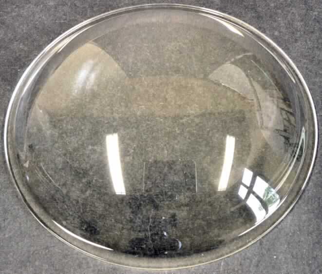 Sog. "Linse (komplett aus Glas). Art. 8K6010"
Bei der Ware handelt es sich um einen runden, geschliffenen und polierten Glaskörper mit einem Durchmesser von ca. 11 cm, welcher an einer Seite flach und an der anderen gewölbt gearbeitet ist.
Das Erzeugnis wird zur dekorativen Lichtstreuung an einem Beleuchtungskörper befestigt. Es stellt damit einen Lampenschirm zur Ausstattung eines elektrischen Beleuchtungskörpers dar.

Die Ware ist als "erkennbares Teil zum Ausstatten von elektrischen Beleuchtungskörpern, aus Glas" einzureihen.