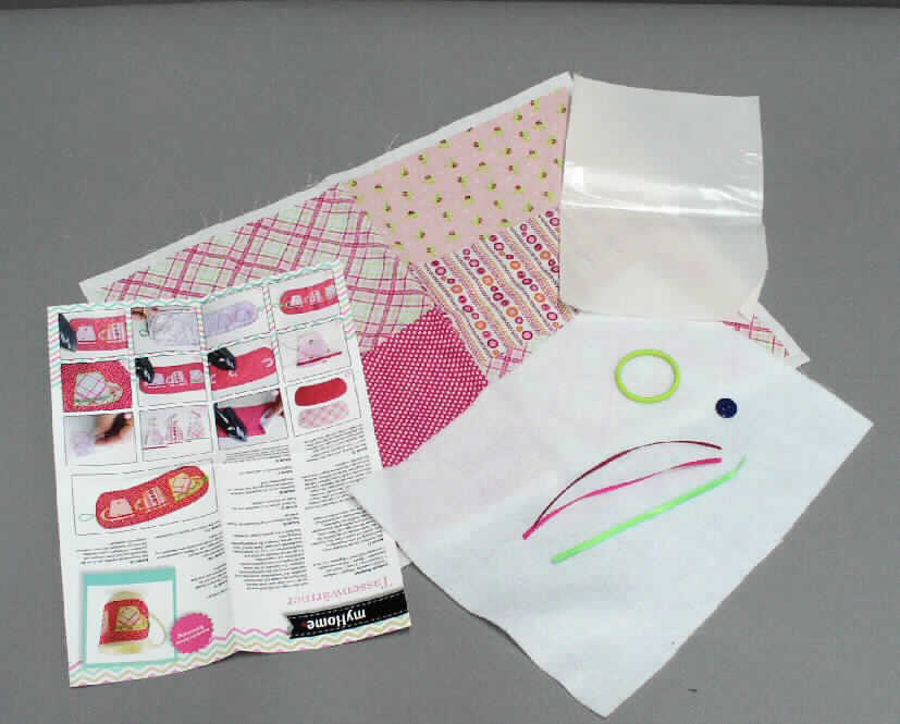 Handarbeitsset, sog. Nähset Tassenhülle für Kinder, Order 502871, Fotos siehe Anlage,
- bestehend aus einem Gewebe, einem Vliesstoff, einer Folie, drei Bändern, einem Gummiband, einem Knopf 
  und einer Anleitung; 
- als Warenzusammenstellung gemeinsam in einer Papptüte mit klarsichtigem Kunststofffenster für den 
  Einzelverkauf aufgemacht und zur Befriedigung eines speziellen Bedarfs zusammengestellt, 
- Gewebe:
-- rechteckig zugeschnitten, mit den Abmessungen: ca. 43 cm x 32,5 cm,
-- laut Antrag aus 100 % Baumwolle,
-- in Leinwandbindung,
-- mit einem Quadratmetergewicht von laut Antrag 130 g,
-- bedruckt (nicht nach dem Batik-Verfahren handbedruckt),
-- nicht auf Handwebstühlen hergestellt,
-- wird zur Herstellung der beiden Schauseiten der "Tassenhülle" und zur Herstellung der Tassenmotive verwendet,
- Vliesstoff:
-- rechteckig zugeschnitten, mit den Abmessungen: ca. 29 cm x 21,5 cm,
-- aus Spinnstoff (laut Antrag: 100 % Polyester),
-- einseitig punktuell mit einem Schmelzkleber versehen,
-- wird als Verstärkung (Zwischenlage) verwendet,
- Folie (sog. Bügelfolie):
-- rechteckig zugeschnitten, mit den Abmessungen: ca. 21,5 cm x 15,5 cm,
-- aus Kunststoff (laut Antrag: 100 % Polyester),
-- dient zum Aufbügeln der Vliesunterlagen auf die Gewebezuschnitte,
- Bänder (sog. Satinbänder): 
-- drei Stück als Streifen in verschiedenen Farben (grün, magenta, granatrot), mit den Abmessungen: 
   ca. 15 cm x 0,4 cm,  
-- aus glatten, einfarbigen Geweben aus Chemiefasern, in Atlasbindung,
-- mit echten Webkanten,
-- werden als Zierelemente aufgenäht,
- Gummiband,
-- ringförmig zusammengenäht (Durchmesser: ca. 4,5 cm), mit einer Dicke von ca. 3 mm,
-- aus einem elastischen Band aus augenscheinlich Kautschuk, das mit einfarbigen Spinnstoffgarnen umflochten ist,
-- wird als Verschlussschlaufe verwendet,
- Knopf,
-- rund, mit einem Durchmesser von ca. 1,5 cm,
-- aus Kunststoff,
-- mit zwei Nählöchern, 
-- wird als Verschluss verwendet,
- Anleitung:
-- mit den Abmessungen: ca. 28 cm x 21 cm,
-- in Form eines mit Texten und Abbildungen bedruckten Blattes aus Papier, 
-- wird als Anleitung und Schnittmustervorlage verwendet,
- dient zur Herstellung eines dekorativen Tassenwärmers,
- im Hinblick auf die Verwendung als Tassenwärmer sind der Vliesstoff und das Gewebe annähernd gleich-
  bedeutend; insbesondere im Hinblick auf den Wert verleiht jedoch das Gewebe der Warenzusammenstellung
  ihren wesentlichen Charakter.

"Gewebe aus Baumwolle, mit einem Anteil an Baumwolle von mehr als 85 GHT und einem Quadratmetergewicht
 von weniger als 200 g, bedruckt, in Leinwandbindung, mit einem Quadratmetergewicht von mehr als 100 g,
 nicht auf Handwebstühlen hergestellt, nicht nach dem Batik-Verfahren handbedruckt"