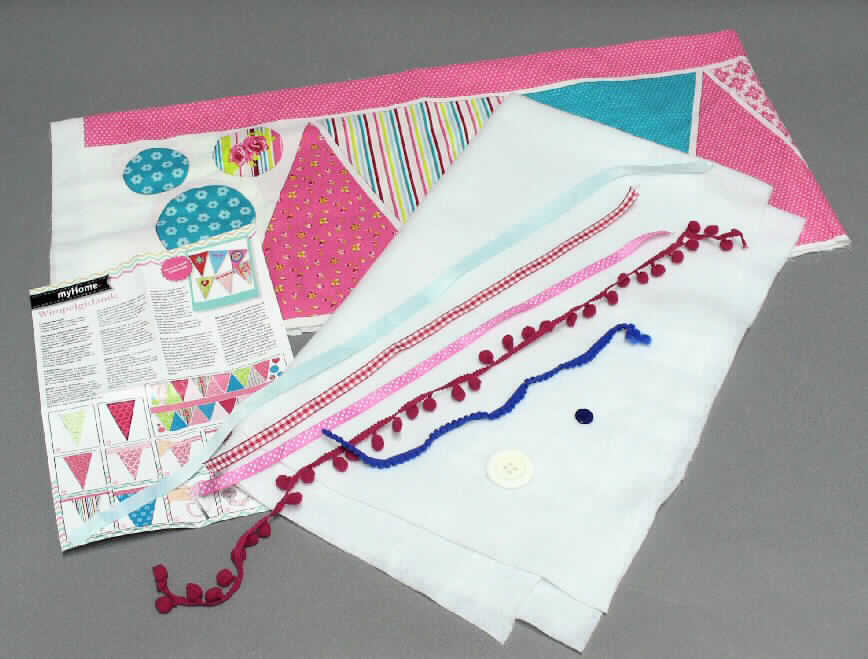 Handarbeitsset, sog. Nähset Wimpel für Kinder, Order 502874, Fotos siehe Anlage,
- bestehend aus einem Gewebe, einem Vliesstoff, drei Bändern, zwei Häkelgalonbändern, zwei Knöpfen
  und einer Anleitung; 
- als Warenzusammenstellung gemeinsam in einer Papptüte mit klarsichtigem Kunststofffenster für den 
  Einzelverkauf aufgemacht und zur Befriedigung eines speziellen Bedarfs zusammengestellt, 
- Gewebe:
-- rechteckig zugeschnitten, mit den Abmessungen: ca. 144 cm x 61 cm,
-- laut Antrag aus 100 % Baumwolle,
-- in Leinwandbindung,
-- mit einem Quadratmetergewicht von laut Antrag 130 g,
-- bedruckt (nicht nach dem Batik-Verfahren handbedruckt),
-- nicht auf Handwebstühlen hergestellt,
-- wird zur Herstellung der jeweils beiden Schauseiten eines Wimpels, des Aufhängebandes und der Zierelemente 
   verwendet,
- Vliesstoff:
-- rechteckig zugeschnitten, mit den Abmessungen: ca. 103 cm x 63 cm,
-- aus Spinnstoff (laut Antrag: 100 % Polyester),
-- einseitig punktuell mit einem Schmelzkleber versehen,
-- wird als Verstärkung (Zwischenlage) verwendet,
- Bänder: 
-- drei Stück in Streifen, 
-- mit echten Webkanten,
-- in verschiedenen Ausführungen:
--- als sog. Satinband: mit den Abmessungen: ca. 69 cm x 1,3 cm; aus glatten, einfarbigen Geweben aus 
    Chemiefasern, in Atlasbindung,
--- als sog. Ripsband: mit den Abmessungen: ca. 50 cm x 1 cm; aus bedruckten (mit Punkten) Geweben aus 
    Chemiefasern, in Atlasbindung,
--- als sog. Ginghamband: mit den Abmessungen: ca. 50 cm x 1 cm: aus buntgewebten Geweben aus 
    Chemiefasern, in Leinwandbindung,
-- werden als Zierelemente aufgenäht,
- Häkelgalonbänder (sog. Pomponbänder):
-- zwei Stück in Streifen,
-- aus Kettengewirken aus Chemiefasern,
-- in verschiedenen Ausführungen, 
--- als sog. Pomponband mit großen Pompons: mit den Abmessungen: ca. 70 cm x 2 cm; mit angewirkten 
    Pompons mit einem Durchmesser von ca. 10 mm,
--- als sog. Pomponband mit kleinen Pompons: mit den Abmessungen: ca. 33 cm x 1 cm; mit seitlich 
    herausgezogenen Schüssen in der Optik eines "Pompons" mit einem Durchmesser von ca. 5 mm,
-- werden als Zierelemente aufgenäht,
- Knöpfe,
-- aus Kunststoff,
-- in zwei verschiedenen Ausführungen:
--- als blauer Knopf: rund und flach, mit einem Durchmesser von ca. 1,5 cm; mit zwei Nählöchern, 
--- weißer Knopf: rund, mit reliefartigem Rand, mit einem Durchmesser von ca. 3,8 cm, mit vier Nählöchern,
-- werden als Zierelemente aufgenäht,
- Anleitung:
-- mit den Abmessungen: ca. 28 cm x 21 cm,
-- in Form eines mit Texten und Abbildungen bedruckten Blattes aus Papier,  
-- wird als Nähanleitung verwendet,
- dient zur Herstellung einer Wimpelgirlande,
- im Hinblick auf den Umfang, die Bedeutung in Bezug auf die Verwendung und den Wert verleihen die Gewebe 
  der Warenzusammenstellung ihren wesentlichen Charakter.

"Gewebe aus Baumwolle, mit einem Anteil an Baumwolle von mehr als 85 GHT und einem Quadratmetergewicht
 von weniger als 200 g, bedruckt, in Leinwandbindung, mit einem Quadratmetergewicht von mehr als 100 g,
 nicht auf Handwebstühlen hergestellt, nicht nach dem Batik-Verfahren handbedruckt"