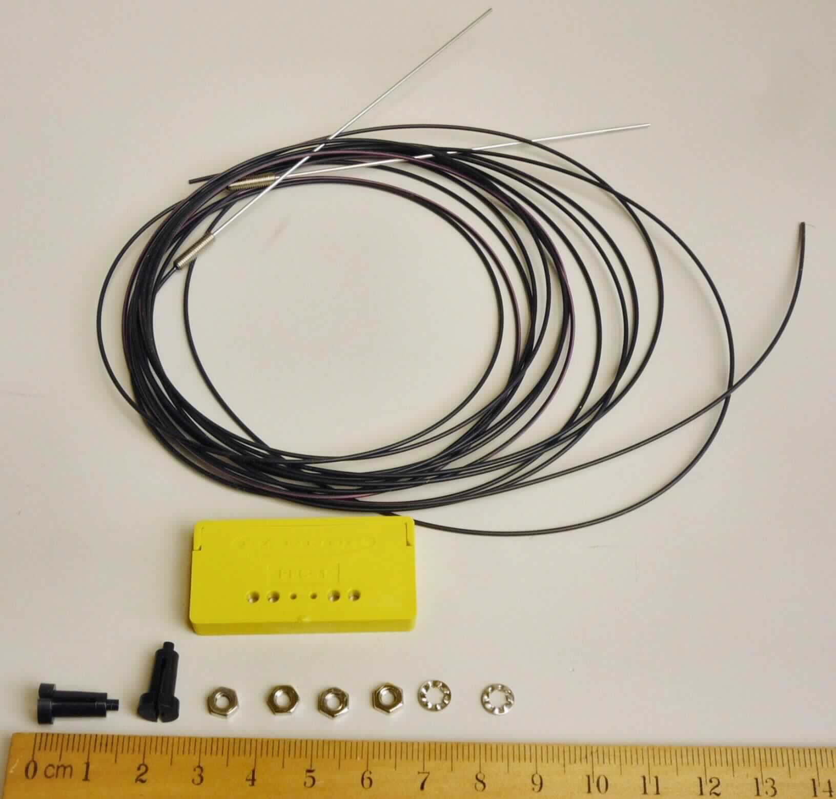 Kunststoff Lichtleiter,
optisches Faserkabel aus Kunststoff mit einer einzeln umhüllten Kunststofffaser, mit einem Kern von 0.5 mm Durchmesser, versehen mit einem sog. Cladding und einem Kabelmantel aus Polyethylen, an einem Ende mit einem länglichen, zylinderförmigen Anschlussstück aus Stahl mit Schraubgewinde ausgerüstet. 
Zwei Lichtwellenleiter (charakterbestimmend in Bezug auf die Verwendung) sind in Form einer Warenzusammenstellung in Aufmachung für den Einzelverkauf mit einem Schneidwerkzeug zum Kürzen der Lichtwellenleiter sowie Befestigungsmaterial in einem Karton verpackt.

Die Zusammenstellung ist als "Kabel aus optischen, einzeln umhüllten Fasern, auch mit Anschlussstücken versehen" einzureihen.