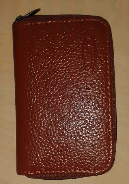 Geldbörse, Taschen- oder Handtaschenartikel, sog. Geldbeutel, Foto siehe Anlage, 
- mit einer Außenseite aus Leder (laut Antrag Rindsleder), 
- mit einem dreiseitig umlaufenden Reißverschluss, 
- aufklappbar,
- innen:
- - gefüttert,
- - auf beiden Seiten jeweils mit einem Einsteckfach im Scheckkartenformat, 
- - in der Mitte mit einem Reißverschlussfach als Trennsteg,
- in den Abmessungen: ca. 11 cm (Höhe) x  7 cm (Breite) x 2 cm (Tiefe),
- ohne Hinweise auf Handarbeit.
 
"Geldbörse, Taschen- oder Handtaschenartikel, mit Außenseite aus Leder, nicht handgearbeitet"