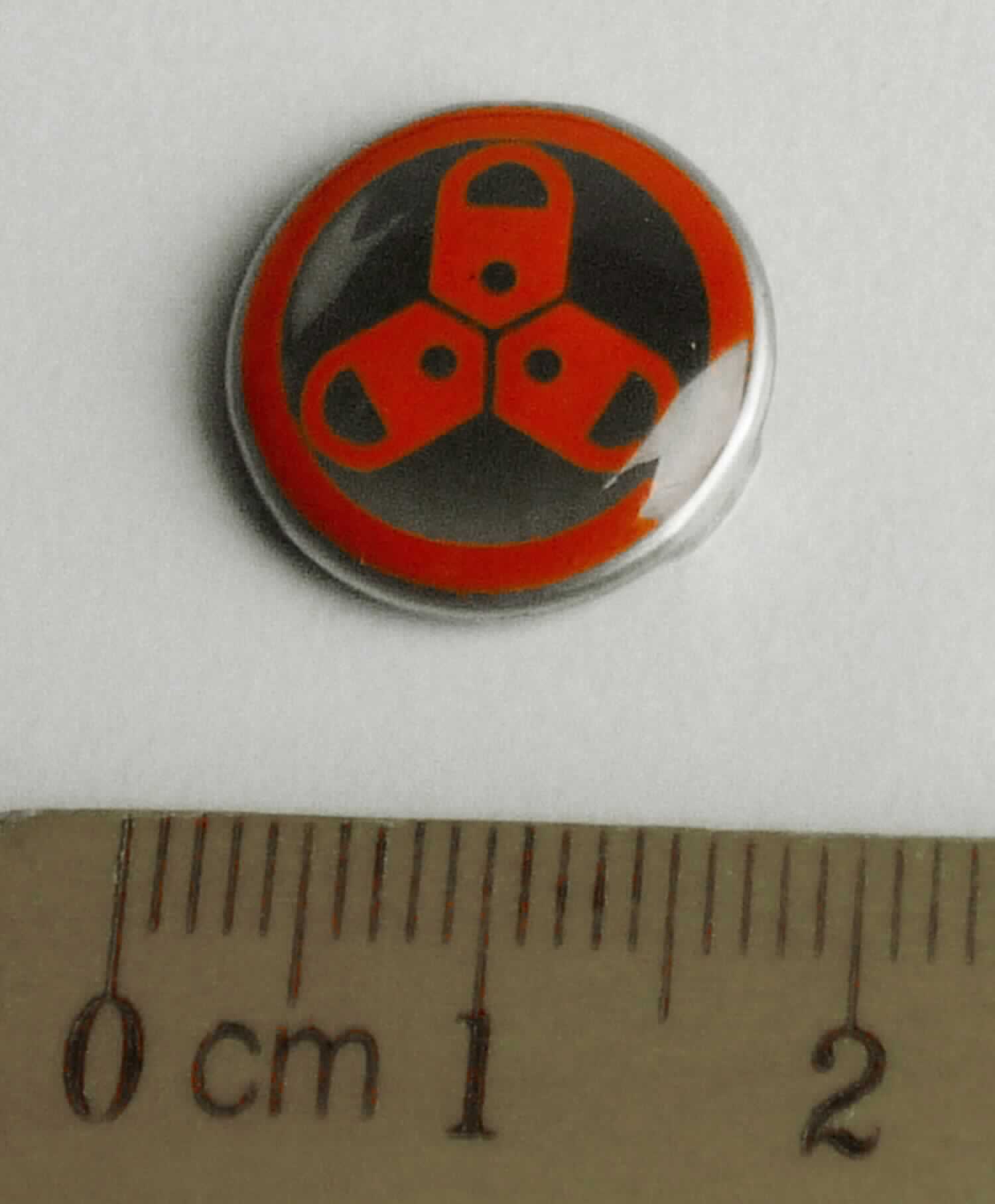 Bei dem vorliegenden Warenmuster handelt es sich um ein kreisrundes, silberfarbenes Erzeugnis (Durchmesser etwa 1,5 cm) aus unedlem Metall, mit Metallkrallen und einem Klebestreifen auf der einen Innenseite. Das Erzeugnis ist auf der Schauseite mit einem Firmenlogo bedruckt. Das Erzeugnis soll mittels der Metallkrallen und des Klebestreifens an einer Fahrradlampe zur Kenntlichmachung eines Markenproduktes befestigt werden. 
- Antragstellerangaben -

Abbildung siehe Anlage. 

Derartige Waren gehören als "den Namensschildern ähnliche Schilder, aus unedlen Metallen" zur Codenummer 8310 0000 00 0 des Zolltarifs.