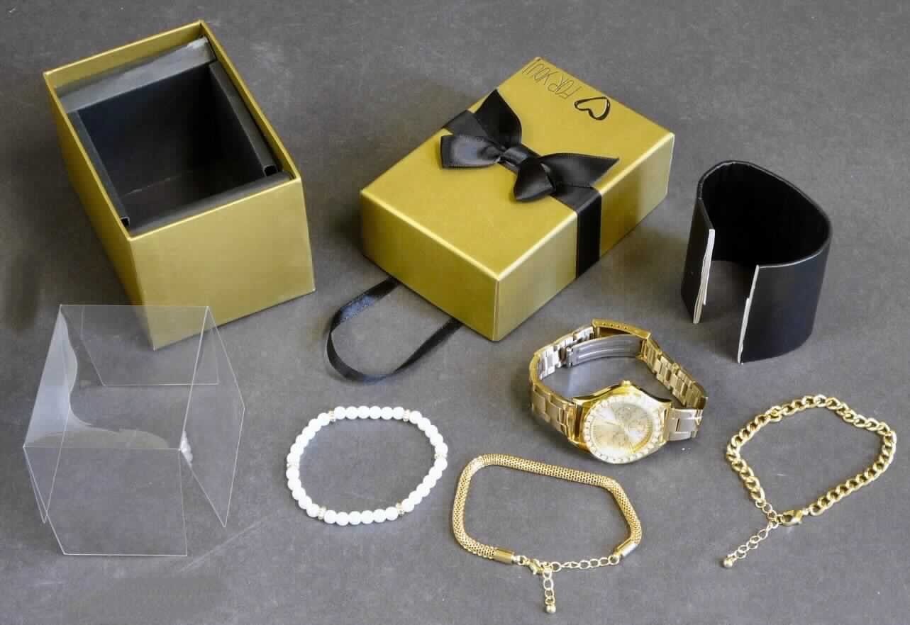 Es handelt sich um einen Bestandteil des Art. 388-268 "Uhr und Armbänder in Geschenkverpackung"-Sets, in Form einer Armbanduhr, elektrisch betrieben (Batterie), mit mechanischer Anzeige (Stunde, Minute, Sekunde), einem mit Strasssteinen verzierten Gehäuse (Durchmesser ca. 3,5 cm) und Armband aus unedlem Metall.

Die Uhr ist gemeinsam mit drei Armbändern (nicht Gegenstände dieser vZTA) in einem Geschenkkarton mit entsprechendem Pappeinlieger zur Auffädelung der Uhr und Armbänder verpackt. Die Bestandteile des Sets sind aufgrund des fehlenden gemeinsamen Bedarfes getrennt voneinander einzureihen.

Die Uhr ist als "andere als in Position 9101 erfasste Armbanduhr, elektrisch betrieben, nur mit mechanischer Anzeige" einzureihen.