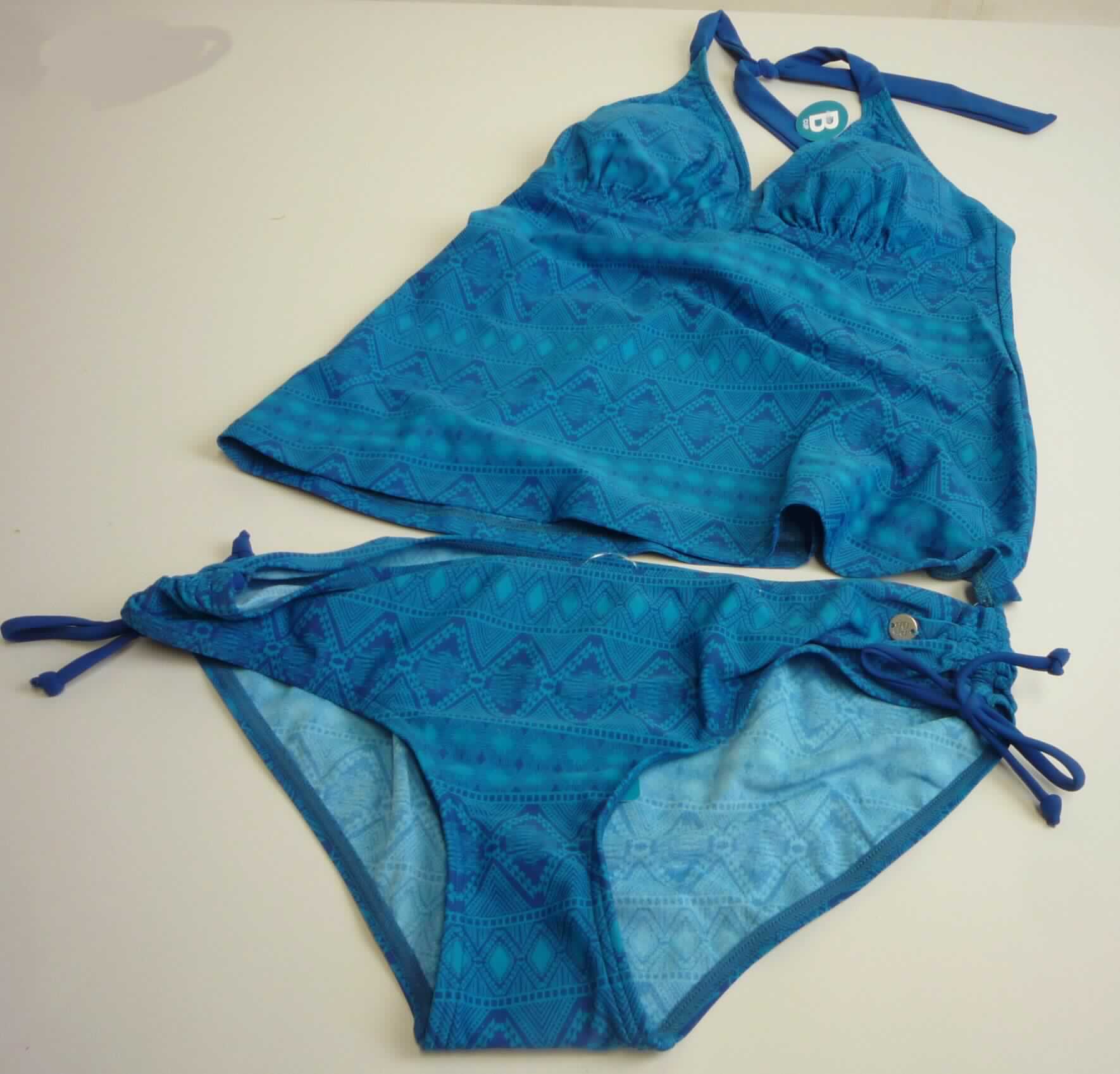 Modisches Unterhemd und Badehose, sog. Damen Tankini, Art. 155921 Farbe 819 royal, Größe 38 B,
Foto siehe Anlage,
- in einem Polybeutel verpackt,
- aus ca. 0,6 mm dicken (leichten), bedruckten Gewirken aus laut Antrag 80 % Polyamid und 20 % Elasthan 
  (beides synthetische Chemiefasern); keine Kautschukfäden enthaltend, die Elastizität ergibt sich durch die
  Verwendung von Elastomergarnen,
- kein zweiteiliger Badeanzug, da das Oberteil aufgrund seines Schnitts nicht erkennen lässt, dass es
  ausschließlich oder hauptsächlich dazu bestimmt ist, als Badekleidung getragen zu werden,
- keine Kombination, u. a. weil weder modische Unterhemden der Position 6109 noch Badehosen der Position 
  6112 als Bestandteile einer Kombination zugelassen sind,
- Badehose:
-- im Schritt mit einem Gewirke unterlegt (Hygieneeinlage),
-- in der Taille abschließend; mit einem ca. 1 cm breiten, elastischen Taillenbund,
-- ohne Öffnung und ohne Verschluss,
-- mit hohen Beinausschnitten; seitlich mit Bindebändern, 
-- aufgrund des Schnitts als Mädchenkleidung erkennbar,
-- nach Schnitt, Material und Ausstattung erkennbar dazu bestimmt ist, als Badekleidung getragen zu werden.

"Badehose, aus Gewirken, für Mädchen, aus synthetischen Chemiefasern, keine Kautschukfäden enthaltend"