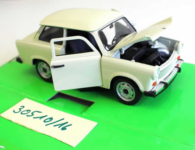 Modellauto, sog. "Trabant 601", Artikel 12217
- im Spritzgussverfahren hergestelltes Modell eines Personenkraftfahrzeuges in Form eines Trabanten im
  Maßstab 1:24 - lt. Verpackungsangabe
- in den Abmessungen von ca. 14,5 x 6,5 x 5,5 cm (L x B x H)
- mit einer Karosserie aus beigefarben lackierten Metall
- mit Unterboden, Innenraum aus Kunststoff und Rädern aus Kunststoff oder Kautschuk
- mit aufklappbarer Motorhaube und Türen sowie Rädern, die über das Lenkrad bewegt werden
- dient der spielerischen Unterhaltung von Kindern
- in einer Showbox für den Einzelverkauf aufgemacht.

Auf Grund des äußeren Erscheinungsbildes bestimmt das Metall den Charakter der aus verschiedenen Stoffen bestehenden Ware.

Die Ware ist als "anderes als zuvor von der Position 9503 erfasstes Modell, im Gussverfahren hergestelltes Miniaturmodell aus Metall" einzureihen.