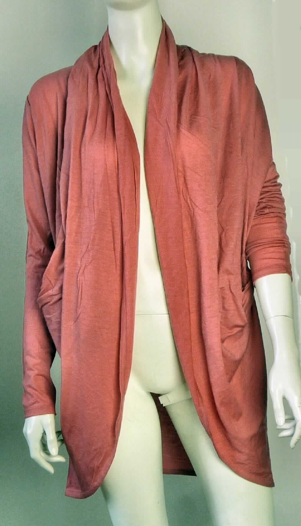 Strickjackenähnliches Kleidungsstück, sog. W04022 Crowdy Bay Cardigan, Größe XS/S, Foto siehe Anlage,
- aus ca. 0,5 mm dicken, einfarbigen Gewirken aus laut Antrag 100 % Merinowolle,
- über den Schritt reichend (Rückenlänge: ca. 73 cm), 
- vorn mit einer durchgehenden Öffnung ohne Verschluss; ohne Hinweise auf den Trägerkreis (unisex); die 
  Vorderteile sind in den Nacken fortlaufend gearbeitet, bilden dort einen locker fallenden "Kragen" und seitlich 
  im Bereich der Taille zwei offene Taschen,
- mit langen Ärmeln, an den Abschlüssen durch Umschlagen und Festnähen gesäumt, 
- am unteren, nach vorne hin abgerundet gearbeiteten Rand gesäumt.

"Strickjackenähnliches Kleidungsstück, aus Gewirken, aus Wolle, für Frauen"