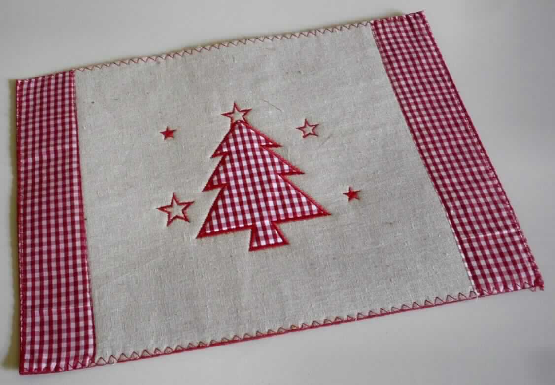 Weihnachts-Platzmatte, Foto siehe Anlage,
- rechteckig, lt. Antrag in den Abmessungen: 40 cm x 29 cm,
- aus Applikationsstickereien in Form eines stilisierten Weihnachtsbaums und stilisierten Sternen auf einem 
  zweilagigen Stickgrund:
-- mit einer die Schauseite bildenden Außenlage aus einfarbigen Geweben aus lt. Antrag 100 % Flachs (Leinen;
   pflanzlicher Spinnstoff des Kapitels 53) und buntgewebten Geweben aus lt. Antrag 100 % Polyester 
   (synthetische Chemiefasern),
-- einer Innenlage aus lt. Antrag Filz aus 100 % Polyester,
- an den Rändern mit einer kontrastfarbenen Überwendlichnaht verziert (somit konfektioniert),
- mit eigenem Gebrauchswert (damit kein Weihnachtsartikel der Position 9505),
- wird insbesondere wegen des Materials üblicherweise nicht gewaschen und kennzeichnet sich aufgrund des 
  Verwendungszwecks als Ware zur Innenausstattung (somit keine Tischwäsche der Position 6302), 
- im Hinblick auf die Verwendung als Platzmatte, das äußere Erscheinungsbild und den Wert ist das aus Flachs 
  gefertigte Gewebe für die Spinnstoffermittlung maßgebend.

"Andere Ware zur Innenausstattung (Weihnachts-Platzmatte), aus Spinnstoffen, keine Ware der Position 9404, 
 andere als in den Unterpositionen 6304 11 bis 6304 93 genannte, aus Stickereien, aus Flachs"