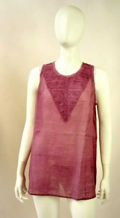 Bluse, sog. Millicent Tunic W04017, Größe S, Foto siehe Anlage,
- aus ca. 0,3 mm dicken, einfarbigen Geweben aus lt. Antrag 65 % Merinowolle und 35 % Seide, 
- über den Schritt reichend (Rückenlänge: ca. 72 cm), vorn bis zu 4 cm kürzer und hinten abgerundet gearbeitet, 
- mit einem runden, leicht halsfernen Ausschnitt,
- hinten mit einer nicht durchgehenden Öffnung mit Knopfverschluss von rechts über links (Frauenkleidung),
- ärmellos,
- mit Brustabnähern; im Brustbereich in Falten abgenäht und mit aufgenähten Bändern aus Klöppelspitze verziert,
- am unteren Rand durch Umschlagen und Festnähen gesäumt.

"Bluse, aus Geweben, für Frauen, aus Wolle"