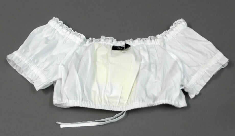 Dreiteilige Zusammenstellung bestehend aus einem Kleid, einem Oberteil (andere Kleidung) und einer Schürze, sog. Dirndl-Set, Order-Nr. 327493, Größe 36, Foto siehe Anlage,
- in Aufmachung für den Einzelverkauf,
- getrennte Einreihung der einzelnen Bestandteile, weil die Kleidungsstücke nicht als Kombination zusammen 
  in eine Position eingereiht werden dürfen, u.a. da das Kleid und die Schürze als Bestandteil einer Kombination 
  nicht zugelassen sind,
- andere Kleidung (Oberteil, sog. Kurzbluse):
- aus ca. 0,3 mm dicken, einfarbigen Geweben aus lt. Antrag 100 % Baumwolle,
- ungefüttert,
- oberhalb der Taille endend (Rückenlänge: ca. 27 cm), somit keine Bluse der Position 6206 und auch kein
  Blouson der Position 6202,
- mit einem halsfernen, runden Ausschnitt; mit einem eingenähten elastischen Band und einer Zierborte 
  ausgestattet; unterhalb des Halsausschnitts bis zum unteren Rand mit zwei eingearbeiteten Bändern, so
  dass das Kleidungsstück in vertikale Richtung gerafft werden kann; damit eindeutig als Frauenkleidung 
  erkennbar,
- ohne Öffnung und ohne Verschluss,
- mit kurzen Ärmeln, im Bereich der Ärmelenden elastisch verengt,
- mit einem verengenden Abschluss am unteren Rand.

"Kleidung, andere als in den Positionen 6201 bis 6210 und in den Unterpositionen 6211 11 bis 6211 20 genannte, 
 aus Geweben, für Frauen, aus Baumwolle, andere als in den Unterpositionen  6211 4210 bis 6211 4242 genannte"
