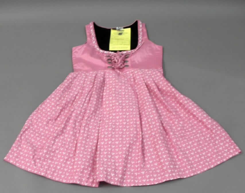 Dreiteilige Zusammenstellung bestehend aus einem Kleid, einem Oberteil (andere Kleidung) und einer Schürze, sog. Dirndl-Set, Order-Nr. 327494, Größe 42, Foto siehe Anlage,
- in Aufmachung für den Einzelverkauf,
- getrennte Einreihung der einzelnen Bestandteile, weil die Kleidungsstücke nicht als Kombination zusammen 
  in eine Position eingereiht werden dürfen, u.a. da das Kleid und die Schürze als Bestandteil einer Kombination 
  nicht zugelassen sind,
- Kleid:
-- oberhalb der Taille aus ca. 0,2 mm dicken, einfarbigen Geweben aus lt. Antrag 100 % Viskose (künstliche 
   Chemiefasern); mit einem Rockteil aus ca. 0,3 mm dicken, buntbedruckten Geweben aus lt. Antrag 100 %
   Baumwolle,
-- über den Schritt reichend (Rückenlänge: ca. 98 cm), kann aufgrund der Länge ohne ein weiteres, den
   Unterkörper bedeckendes Kleidungsstück als Kleid getragen werden,
-- oberhalb der Taille gefüttert,
-- mit einem runden, halsfernen Ausschnitt; am Rand mit einer aufgenähten Zierborte ausgestattet,
-- mit einer kurzen Öffnung vorn; mit acht Zierösen bis zur Taille, durch die in Kreuzbindetechnik ein Bindeband
   eingezogen ist,
-- ohne Ärmel, mit weiten Armauschnitten,
-- seitlich mit einem Reißverschluss,
-- mit einem in der Taille angesetzten, in Falten gelegten Rockteil,
-- nicht nach dem Batikverfahren handbedruckt,
-- an allen Rändern gesäumt,
-- hinsichtlich des Umfangs und des Gesamteindrucks sind die bedruckten Gewebe aus Baumwolle maßgebend.

"Kleid aus Geweben, für Frauen, aus Baumwolle, nicht nach dem Batik-Verfahren handbedruckt"