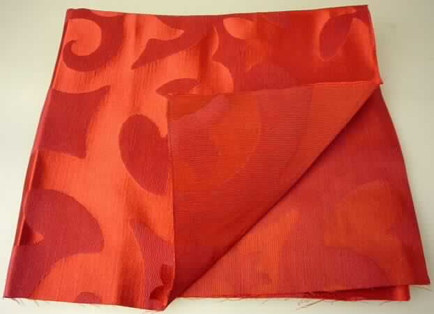 Gewebe, Art. 9-7366 Chilli, Foto siehe Anlage,
- als Meterware,
- mit einer Breite von mehr als 30 cm,
- aus laut Untersuchungsergebnis:
-- Kettgarnen aus Seide, Schussgarnen aus Baumwolle (orangefarbene Garne) und 
   Leinen (dunkelrote Garne),
-- mit einem Gesamtanteil: 
--- an Garnen aus Leinen von 44 GHT,
--- an Garnen aus Seide von 32 GHT,
--- an Garnen aus Baumwolle von 24 GHT,
-- buntgewebt.

"Gewebe aus Flachs (Leinengewebe), mit einem Anteil an Flachs von weniger als 85 GHT, buntgewebt"