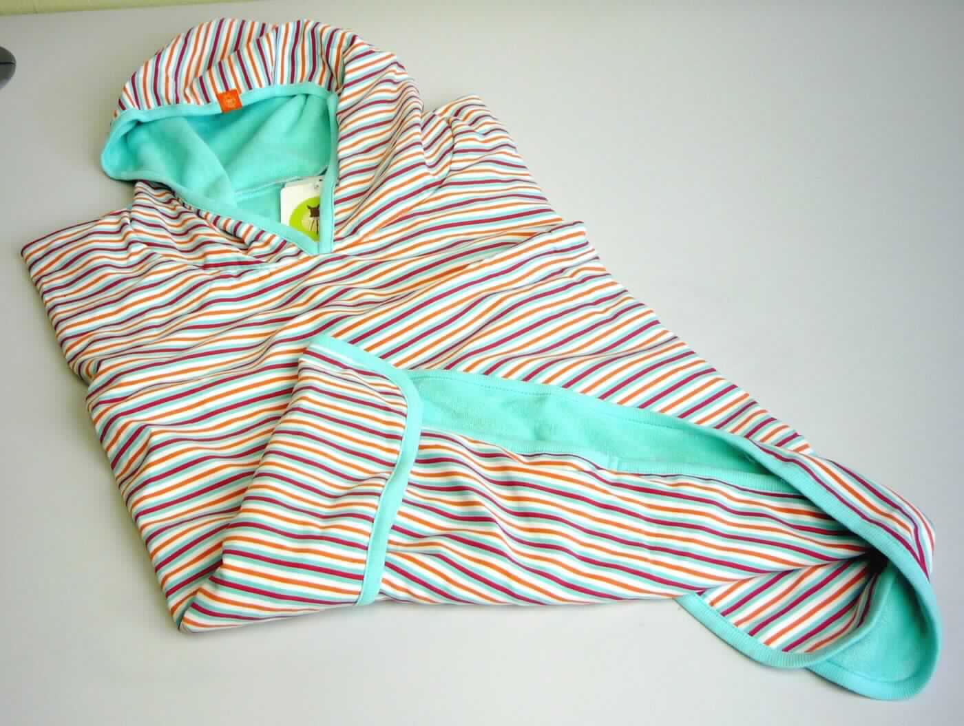 Badeüberwurf, sog. Strandponcho für Kinder, 12-36 Monate (entspricht Größe 74 bis 98), Foto siehe Anlage,
- in einem Polybeutel mit Kunststoffkleiderbügel (übliche Verpackung im Sinne der AV 5 b)) verpackt,
- doppellagig gearbeitet; mit einer Außenlage (Schauseite) aus ca. 0,3 mm dicken, buntbedruckten Geweben aus
  laut Antrag 100 % Polyester (synthetische Chemiefasern) und einer Innenlage aus ca. 1,6 mm dicken, 
  einfarbigen Schlingengewirken aus laut Antrag 80 % Baumwolle und 20 % Polyester,    
- bis über die Knie reichend,
- wird in der Art eines Überwurfs über den Schultern getragen; seitlich offen, die Schultern und Teile der Arme 
  bedeckend,
- mit angenähter Kapuze, deren eingefasster Rand vorn von links auf rechts überlappt (Knabenkleidung), 
- ohne Öffnung und ohne Verschluss,
- an allen Rändern mit einer Randeinfassung versehen,
- wird laut Antrag am Strand oder im Schwimmbad getragen, ist sandabweisend und dient gleichermaßen als 
  UV- und windschützendes Kapuzentuch als auch als schnelltrocknendes Badetuch (u. a. aufgrund der Ausstattung 
  keine Ware der Position 6302),
- ist nicht nur für Kleinkinder mit einer Körpergröße von bis zu 86 cm bestimmt,
- im Hinblick auf die Verwendung sind die Gewebe und Gewirke gleichermaßen von Bedeutung, im Hinblick auf 
  das äußere Erscheinungsbild bestimmen jedoch die Gewebe den Charakter der Ware; wird als den Bademänteln 
  ähnliche Ware aus Geweben vom Warenkreis der Position 6207 genauer erfasst, somit u. a. weder Kleidung 
  der Position 6114 noch der Position 6211.

"Den Bademänteln ähnliche Ware (Badeüberwurf), aus Geweben, für Knaben, aus Chemiefasern"
