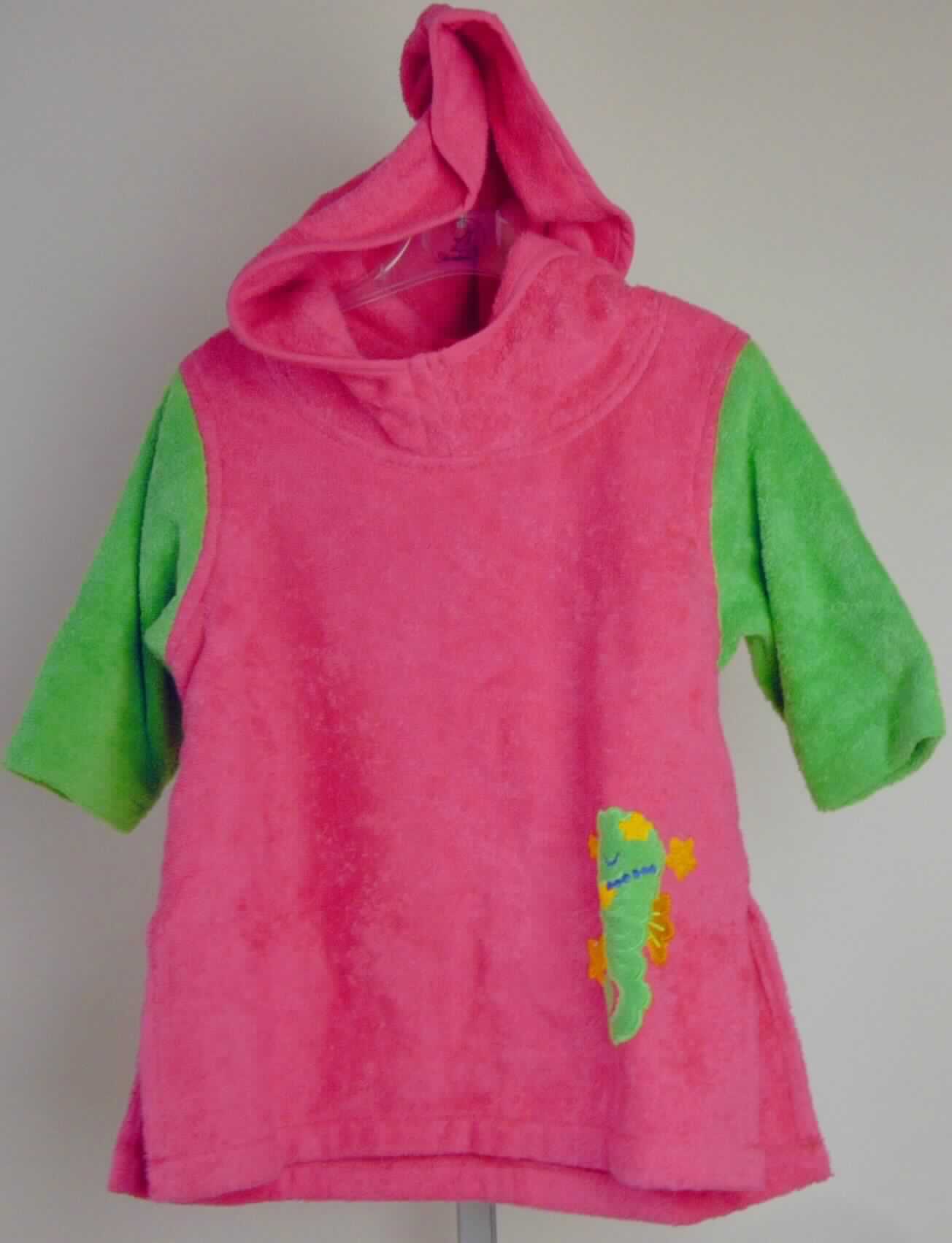 Kleidung für Kleinkinder, sog. Strandkleid für Kinder, Art. 7271480, Größe 74/80, Foto siehe Anlage,
- auf einem Bügel aufgebracht,
- aus verschiedenen, ca. 2,8 mm dicken, einfarbigen Schlingengeweben nach Art der Frottiergewebe mit einem 
  Grund und einer Schlingenoberfläche aus Garnen aus lt. Antrag 100 % Baumwolle,
- über den halben Oberschenkel reichend (Rückenlänge: ca. 48 cm), 
- mit Stehkragen und Kapuze,
- ohne Öffnung und ohne Verschluss,
- mit langen Ärmeln, 
- mit einer Applikationsstickerei verziert,
- am unteren, geraden Rand durch Umschlagen und Festnähen gesäumt, mit ca. 15 cm hoch reichenden 
  Seitenschlitzen,
- aufgrund der Größe für Kinder unter 18 Monaten bestimmt, somit Kleidung für Kleinkinder.

"Kleidung für Kleinkinder, aus Geweben, aus Baumwolle"
