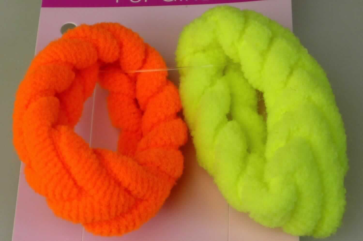 Gewirke, sog. Haargummis Flechtoptik neon, LAN 11948, Foto siehe Anlage,
- als zweiteiliges Sortiment auf einer bedruckten Pappkarte aufgebracht,
- flachliegend mit einer Breite von ca. 3,5 cm; nur geschnitten, somit nicht konfektioniert,
- aus einfarbigen, aufgerollten Schlauchgewirken aus laut Antrag 60 % Polyamid und 40 % Elasthan 
  (Elastomergarn; beides synthetische Chemiefasern),
- kein gewirkter oder gestrickter Samt oder Plüsch, kein Schlingengewirke oder Schlingengestricke.

"Gewirke mit einer Breite von weniger als 30 cm und mit einem Anteil an Elastomergarnen von mehr als 5 GHT,
 andere als solche der Position 6001, keine Kautschukfäden enthaltend, aus synthetischen Chemiefasern"