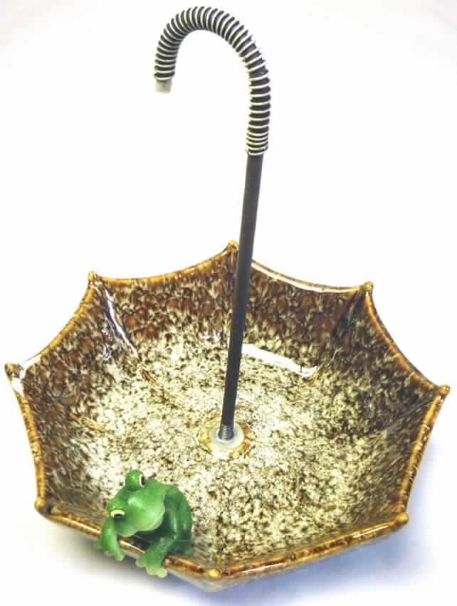 Andere keramische Ware, sog. "Vogeltränke aus Steinzeug", Foto siehe Anlage,
- aus verschiedenen Stoffen zusammengesetzte Ware bestehend aus 
-- einer glasierten, schalenartigen Tränke für Vögel in Form eines aufgespannten
   umgekehrten Schirmes, 
--- mit einer am oberen Rand angearbeiteten Nachbildung eines Frosches verziert,
--- mit einem Durchmesser von 17 cm und einer Höhe von 4 cm, 
--- keramisches Erzeugnis, nach der Formgebung gebrannt, tonmineralhaltiges Material 
    enthaltend, 
--- aus Steinzeug (lt. Antragsangaben),
-- einem mittig in die Schale eingeschraubten "Schirmgriff" aus unedlem Metall,
--- mit einer Länge von ca. 18 cm,
- hinsichtlich der Formgebung und insbesondere in Bezug auf die Verwendung als 
  Ziergegenstand bestimmt die Keramik den wesentlichen Charakter der Ware,
- die Verwendung als Gebrauchsgegenstand (Vogeltränke für den Garten) wird durch die 
  Form und die Verzierung nicht eingeschränkt, somit keine Einreihung in die Position 6913 
  als Ziergegenstand. 

"Zusammengesetzte Ware aus einer anderen keramischen Ware (charakterbestimmend),
 aus Steinzeug und einer anderen Ware aus unedlem Metall"