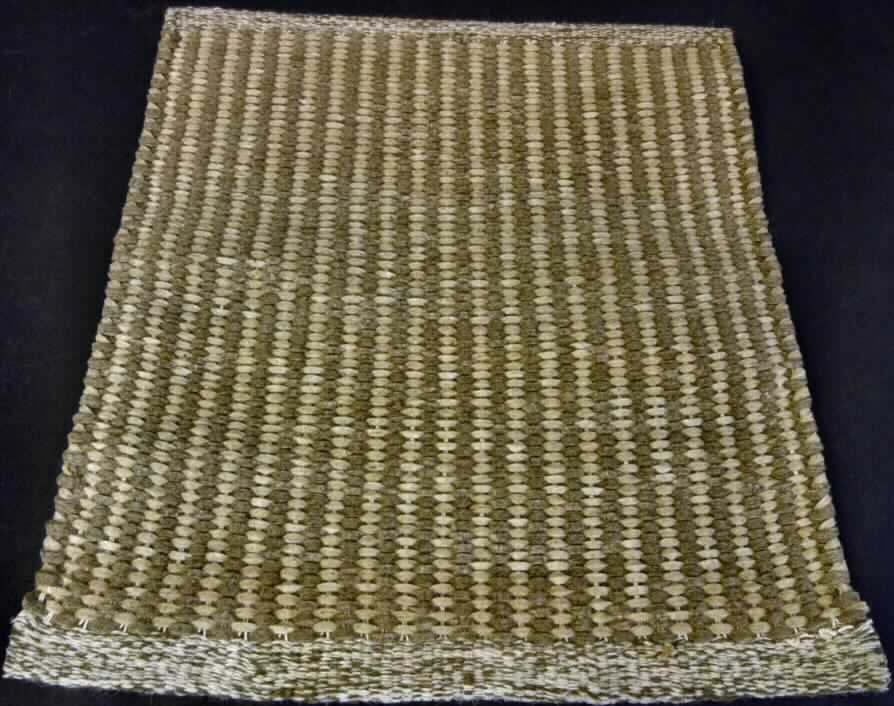 Teppich, sog. Teppich aus Wolle, Foto siehe Anlage,
- wird durch ein Warenmuster in den Abmessungen von etwa 47 cm x 41 cm veranschaulicht, die Ware wird laut
  Antrag in den Abmessungen 140 cm x 200 cm eingeführt, 
- aus buntgewebten Geweben aus laut Antrag Wolle, 
- ohne Flor; weder getuftet noch beflockt,
- an den Schmalseiten durch Umschlagen und Festkleben gesäumt (konfektioniert),
- kein Kelim, Sumak, Karamanie oder ähnlicher Teppich.

"Teppich, aus Spinnstoffen, gewebt, weder getuftet noch beflockt, konfektioniert, kein Kelim, Sumak, Karamanie 
  und ähnlicher handgewebter Teppich, ohne Flor, aus Wolle"