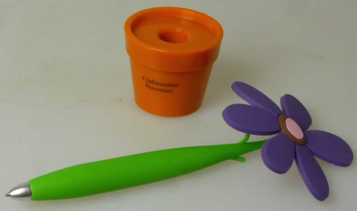 Bei der Ware handelt es sich um eine zusammengesetzte Ware, bestehend aus einem Kugelschreiber in Form einer Blume mit grünem Stamm und einer Blüte und einem Schreibtisch-Aufsteller aus Kunststoff in Form eines Blumentopfes, der mit einer Halterung für einen Stift ausgestattet ist. 

Der Kugelschreiber besitzt eine auswechselbare Mine, die mit blauer Schreibpaste (keine flüssige Tinte) befüllt ist. Der Charakter der zusammengesetzten Ware wird aufgrund der Bedeutung für die Verwendung durch den Kugelschreiber bestimmt.

Die Ware ist als "Kugelschreiber, anderer als mit flüssiger Tinte, mit auswechselbarer Mine" einzureihen.